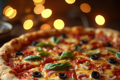 A fresh pizza with mozzarella, pepperoni, and basil, photographed with melted cheese stretching, set on a wooden surface with a warm, bokeh background.